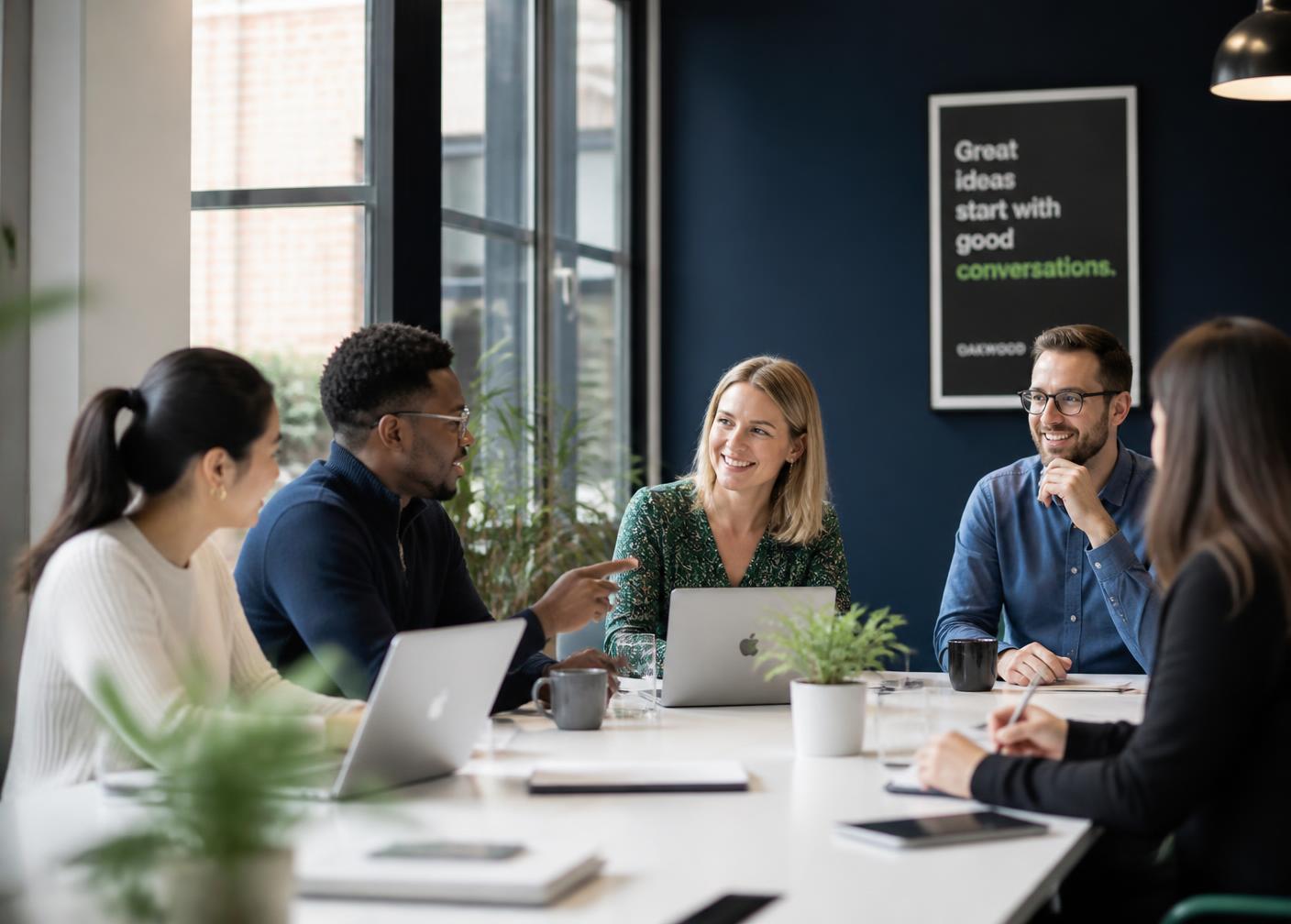 Small business team collaborating around a meeting table with laptops